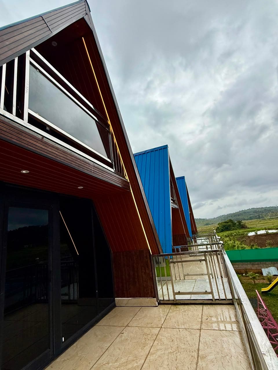 Row of timber chalets and private decks at Mist Wave Resort Panamaram