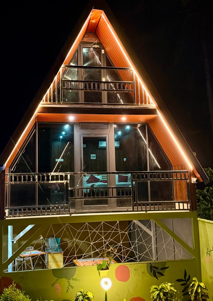 A single chalet lit up at night, glass frontage glowing
