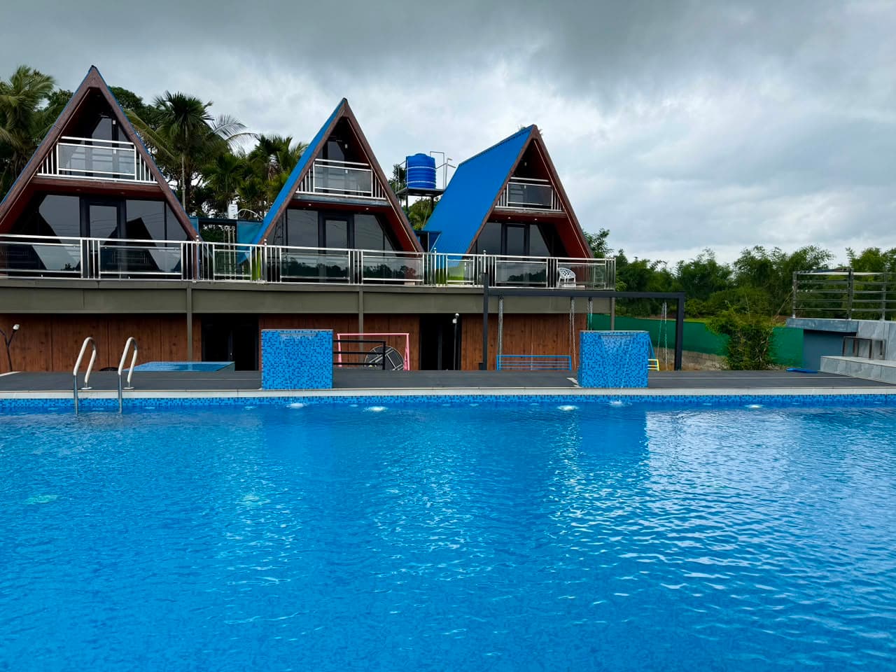 The pool by day with the three blue-roofed chalets behind it