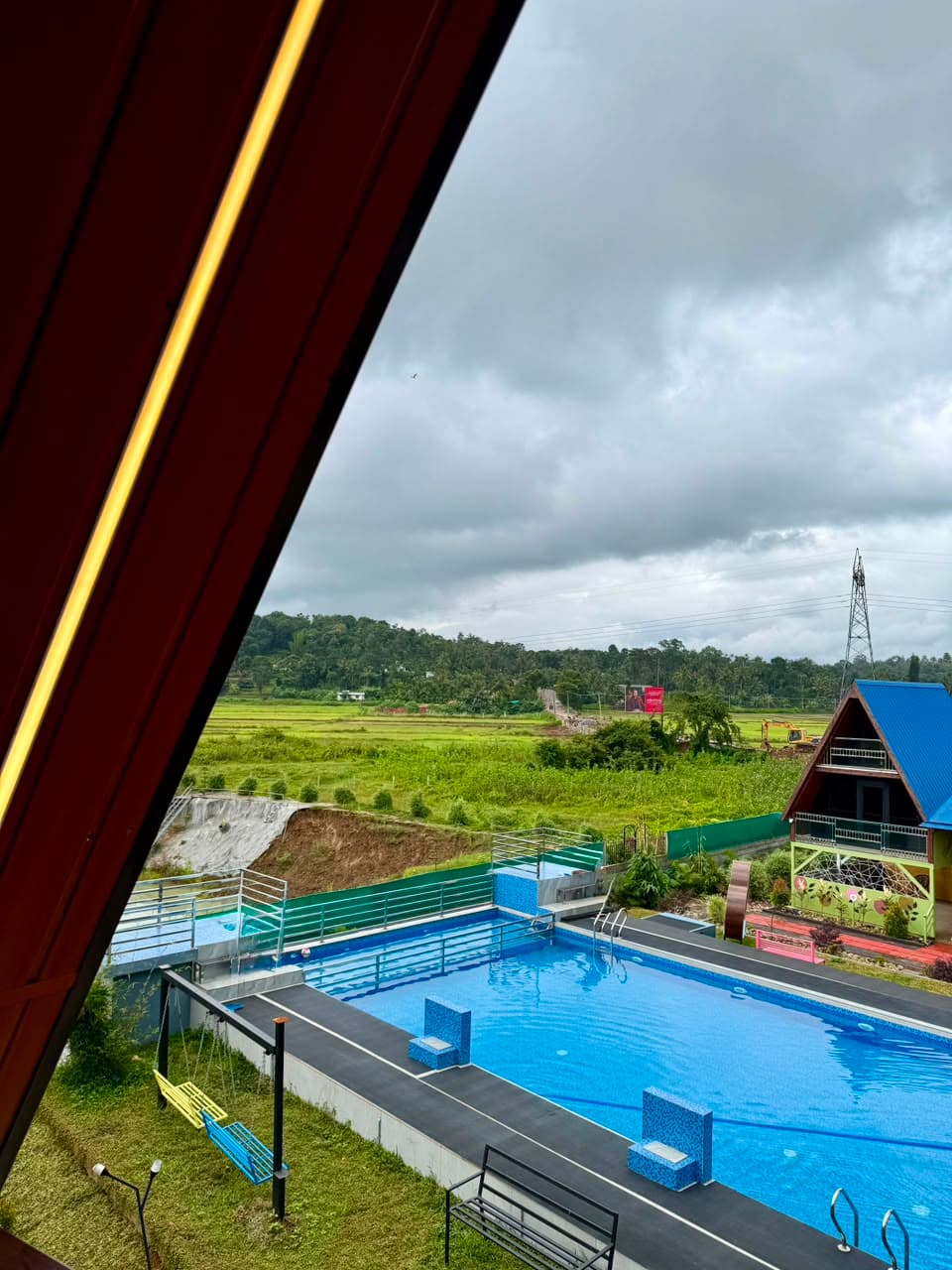 The pool and the open paddy fields beyond, framed by the eave of a chalet